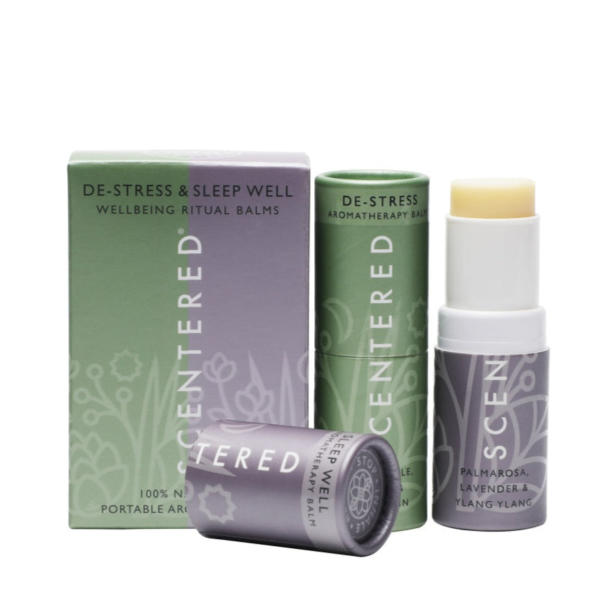 Two aromatherapy balm sticks by Scentered, named the "De - Stress Aromatherapy Balm" and "Sleep Well Therapy Balm," are shown with their packaging. These are 100% natural, portable aromatherapy products crafted for wellbeing rituals, enriched with scents such as palmarosa, lavender, and ylang - ylang.