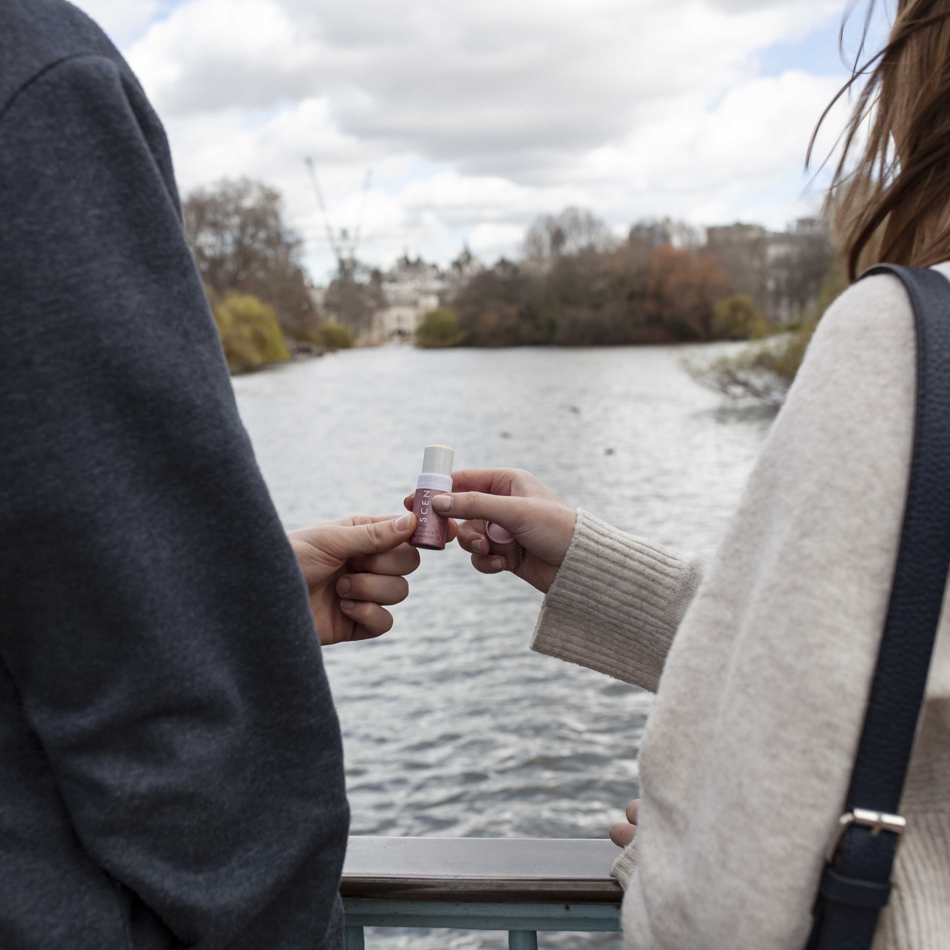Scentered Aromatherapy Love Balm being shared between two people on a bridge, love Therapy Balm by Scentered, a romantic floral blend crafted to inspire feelings of love and emotional connection.
