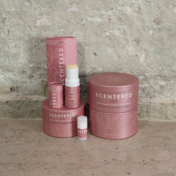Scentered Love product range featuring the Love Home candle, the Love travel candle, the Love aromatherapy balm, and a Love mini aromatherapy balm. Love Therapy Balm by Scentered, a romantic floral blend crafted to inspire feelings of love and emotional connection. Essential oil Rose, Patchouli, Cedarwood Candle for Hormone balance.