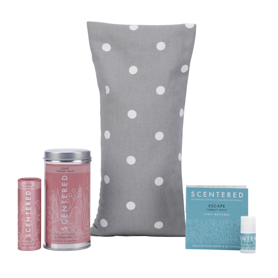 Scentered Love Aromatherapy Balm next to its tin packaging, Wheat bag, and Escape Mini Aromatherapy Balm next to its booklet packaging, nurture your senses with our Love Therapy Balm, balancing hormones and promoting self-care. Portable mindfulness balm by Scentered, perfect for maintaining mental well-being during travel or busy schedules.