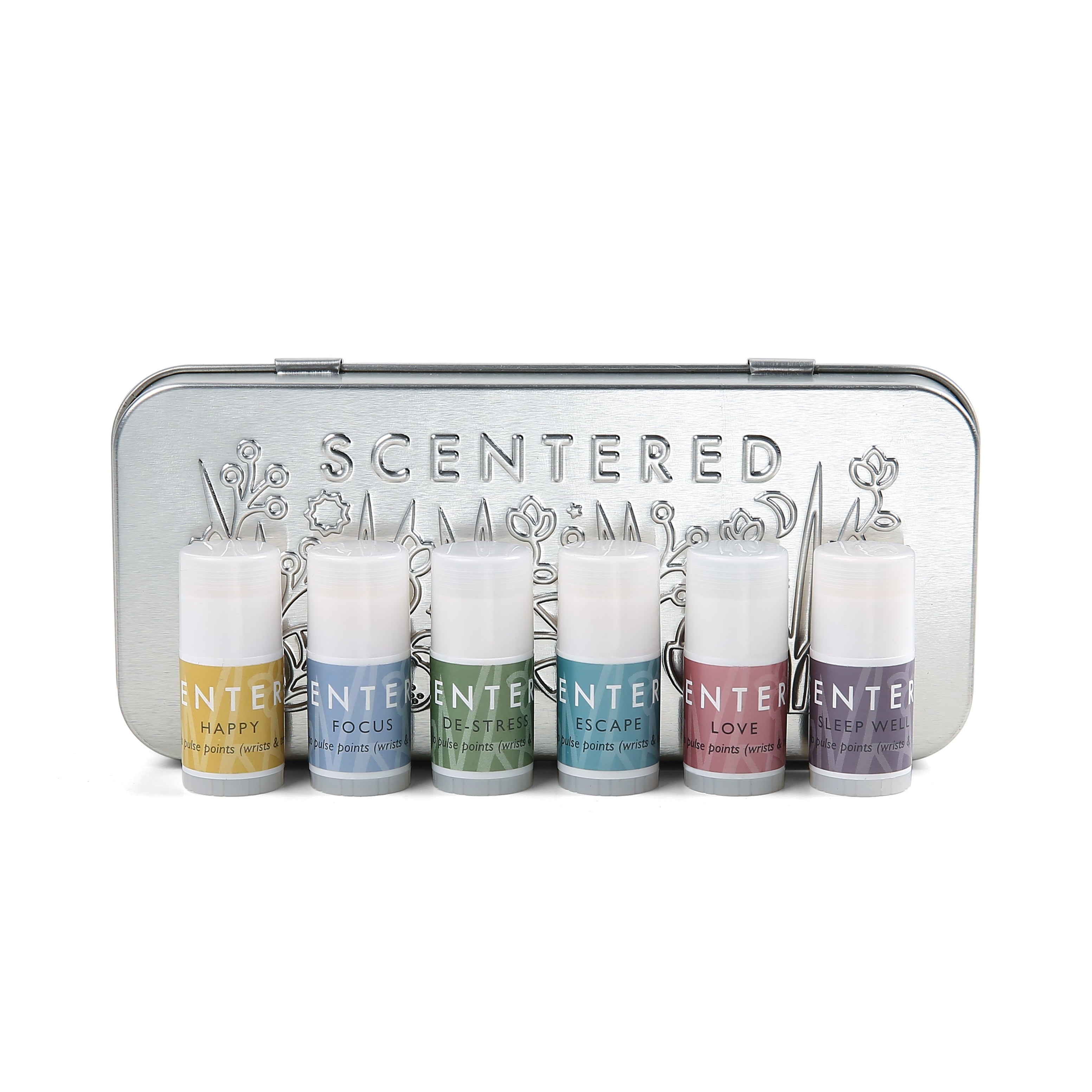 Scentered Aromatherapy Discovery Tin Set closed showing Scentered brand name on front of tin and embossed floral pattern.  In front of the tin  are the 6 aromatherapy balms included in the gift set: Happy, Focus, De-stress, escape, Love and Sleep Well Aromatherapy Mini Pulse point balm sticks 1.5g