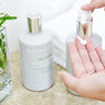 Person's hand pumping the Scentered De-stress Body & Hand Lotion onto their finger tips, next to a bottle of the Scentered De-stress Body & Hand Wash